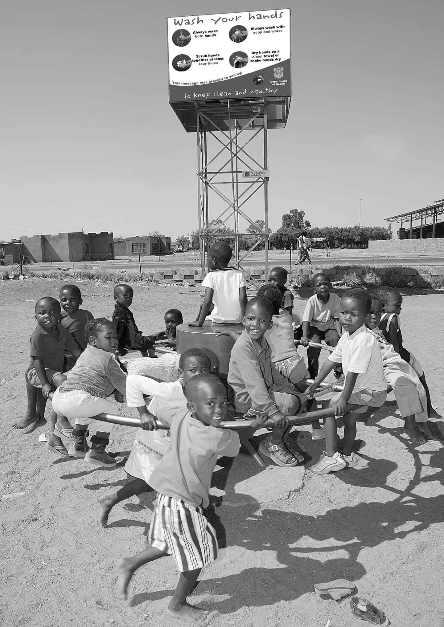 Bild von einer Gruppe von Kindern, die auf einer Playpumpe spielen. Das ist eine Wasserpumpe, die Spielzeugen auf Spielplätzen nachgeahmt ist und wo mithilfe von Drehbewegungen Wasser gefördert werden kann.